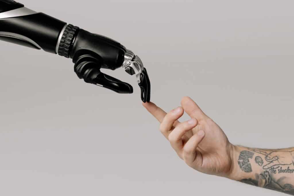 An image of a robot hand touching a human finger, which symbolizes leveraging AI Coaching Technology and an AI Coach.