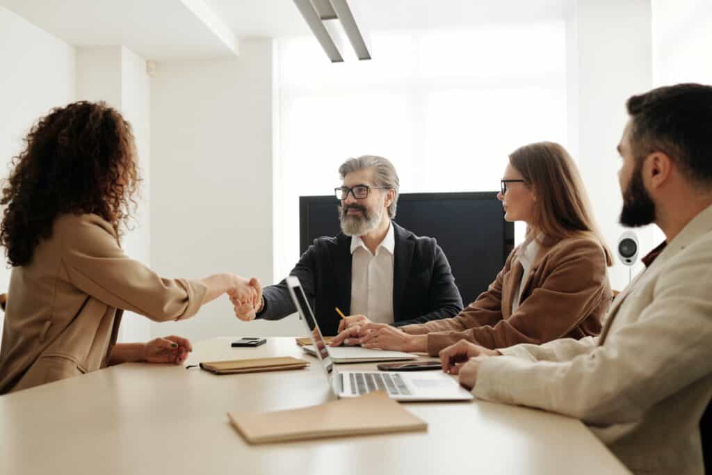 A woman shaking hands with a manager in the interview panel after being offered a job following being sourced through AI Recruitment tools